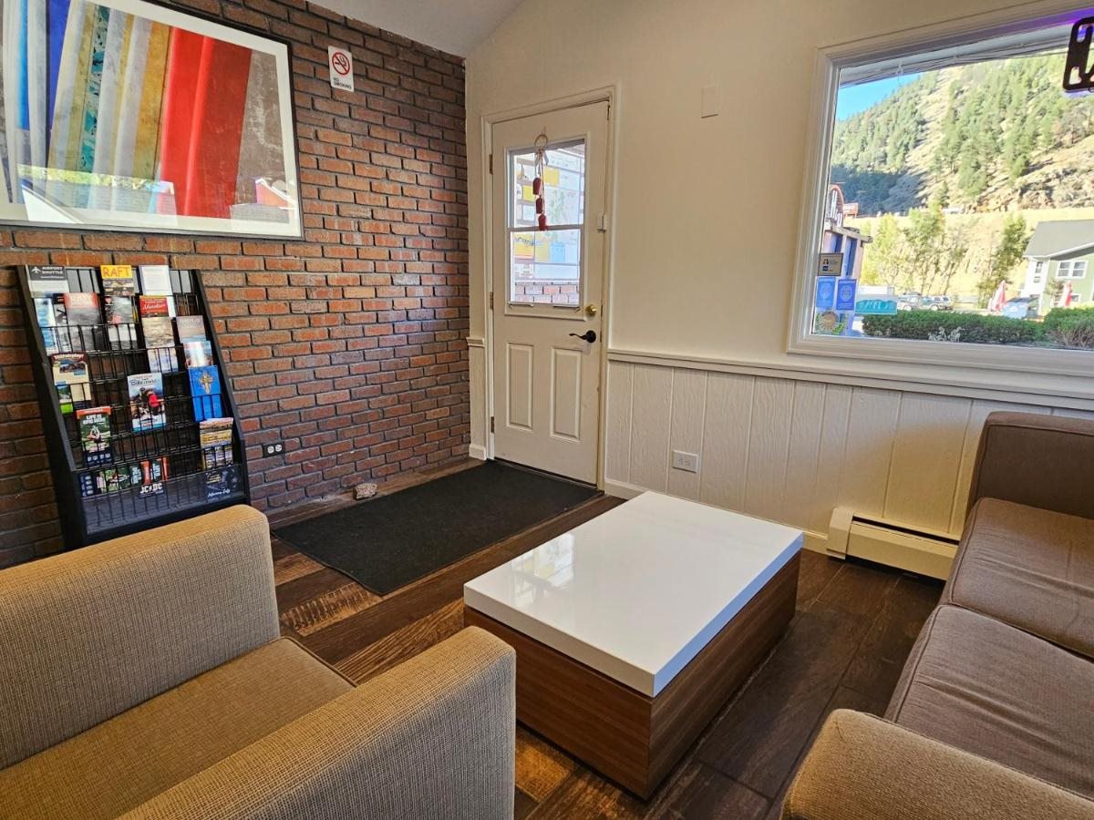 The lobby at H&H Motor Lodge — armchairs around a low table, a brochure rack against the brick wall, and a window looking out to the canyon.